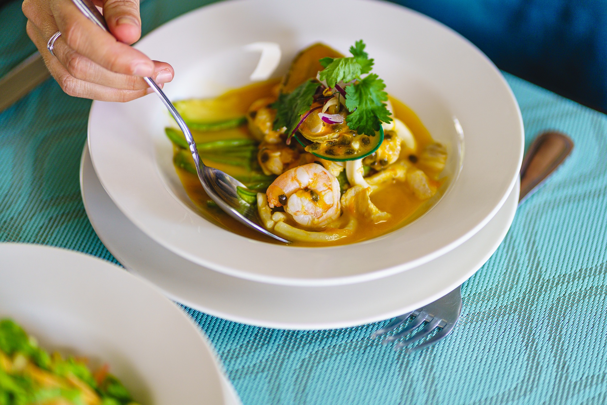 Detail of the hands of a person eating peruvian ceviche with spoon